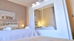 A hotel room with a large mirror, a bed with a white headboard, and a wall-mounted artwork. - Il Girasole Bed and Breakfast (Palermo)