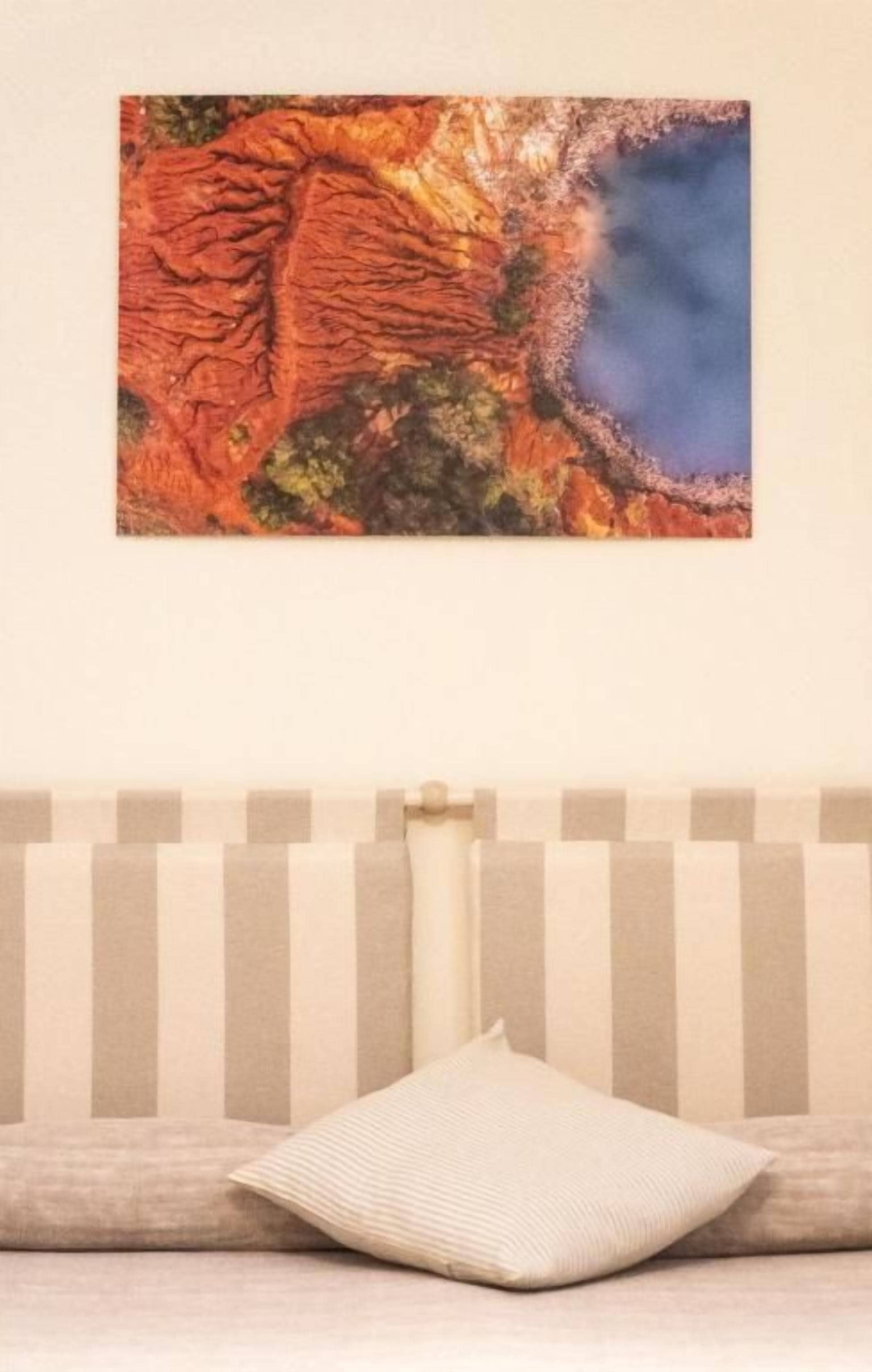 Ein Zimmer mit einem gestreiften Kopfteil, einem Kissen und einem an der Wand befestigten Kunstwerk.