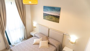 Ein ordentlich eingerichtetes Schlafzimmer mit einem Bett, Nachttischen, einem Gemälde und einer Lampe.