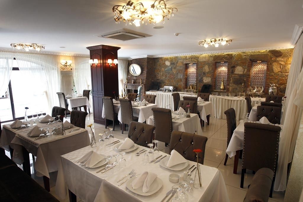 Ein Restaurant mit mehreren Esstischen, das eine Steinwand und Kronleuchter zeigt.