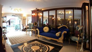 Un salón lujoso con un sofá azul, muebles ornamentados y una araña.