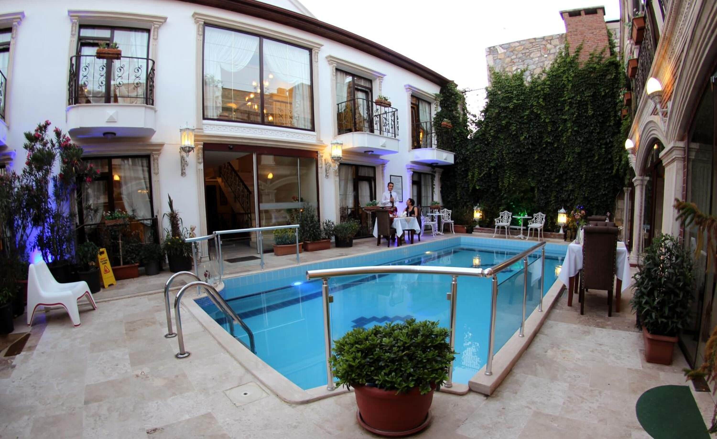 A pool area with a glass barrier, potted plants, and outdoor seating.