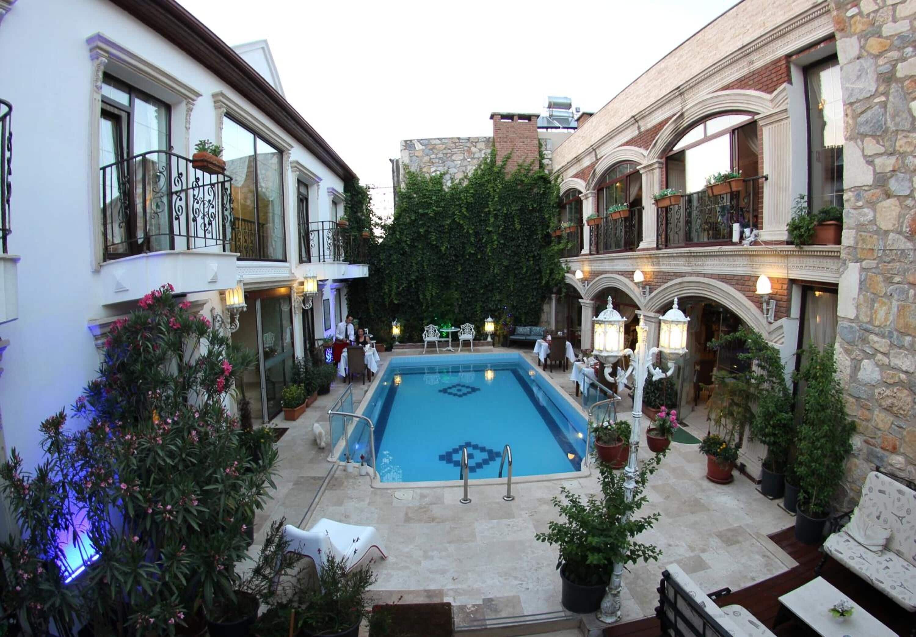 A courtyard with a swimming pool, surrounded by buildings with balconies and potted plants.