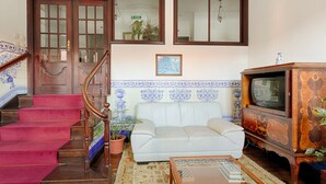 A living room with a staircase, a white sofa, a television, and a decorative cabinet. - Albergaria da Sé (Braga)
