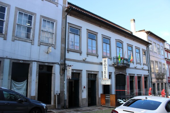Un hotel con diverse finestre, un balcone con bandiere e un cartello che indica che si tratta di un albergo.