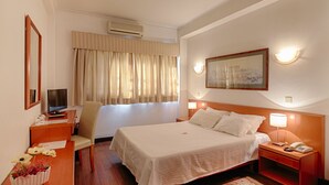 A hotel room with a bed, bedside table, chair, desk, and a desk lamp. - Albergaria da Sé (Braga)