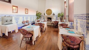 A dining area with tables set for service, chairs, a fireplace, and decorative wall tiles. - Albergaria da Sé (Braga)