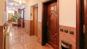 A hotel hallway with a wooden door, a radiator, and a potted plant. - Albergaria da Sé (Braga)
