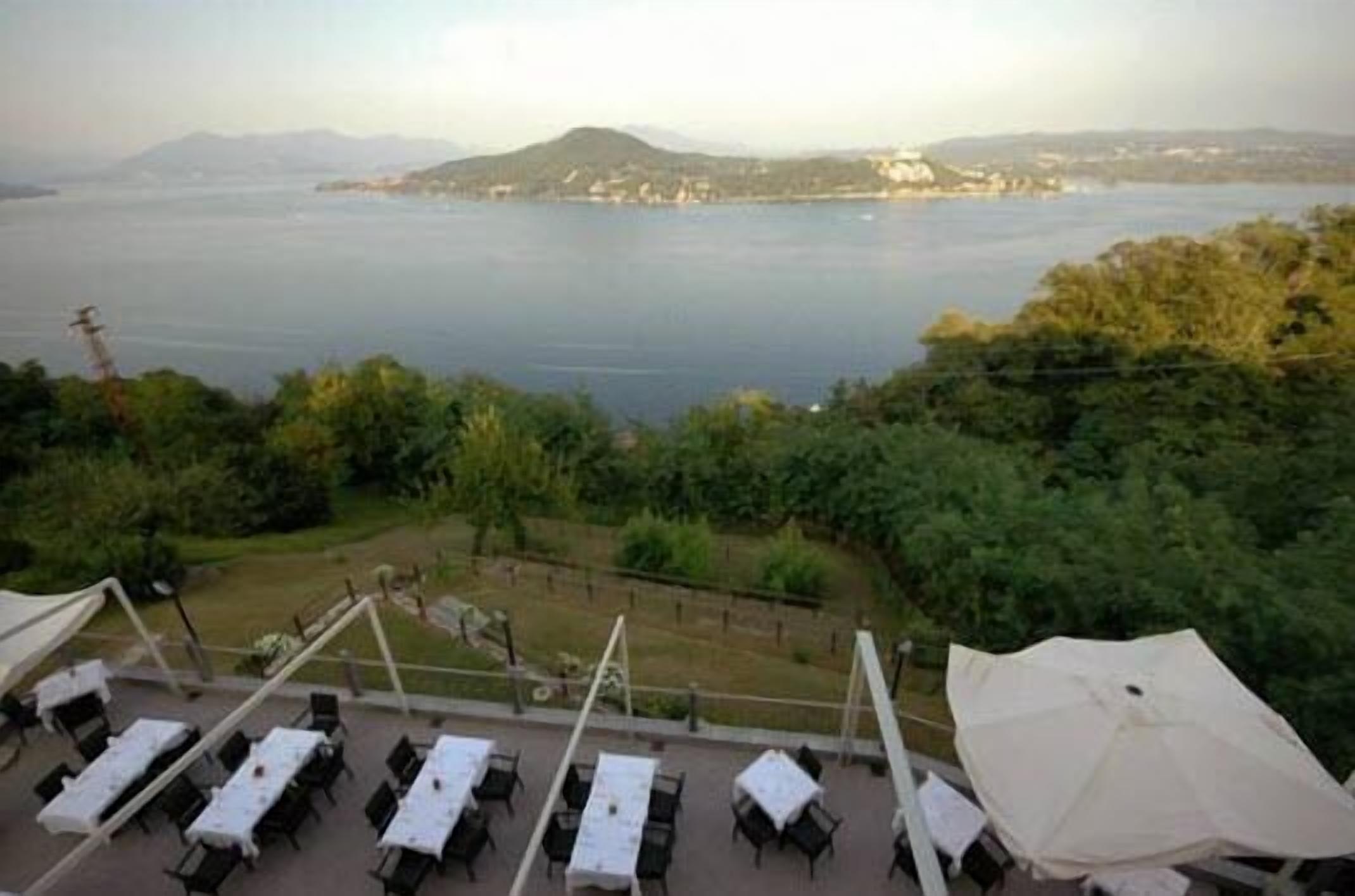A terrace with tables and umbrellas overlooking a body of water and a distant shoreline.