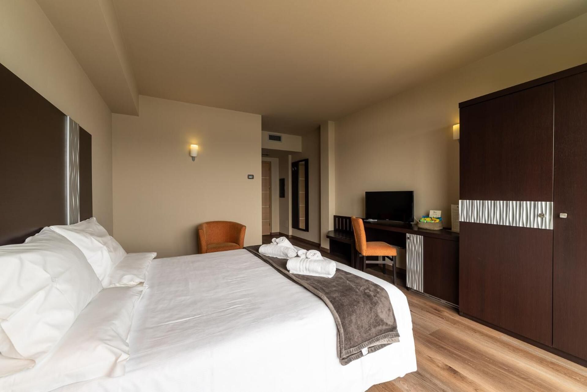 Una camera d'hotel con un letto grande, una scrivania con sedia, una televisione e un armadio.