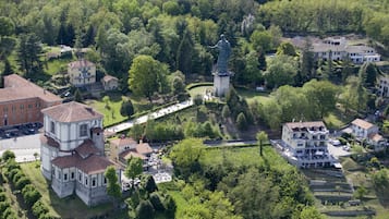 An aerial view of a historic town with a prominent statue, traditional buildings, and a well-maintained park.