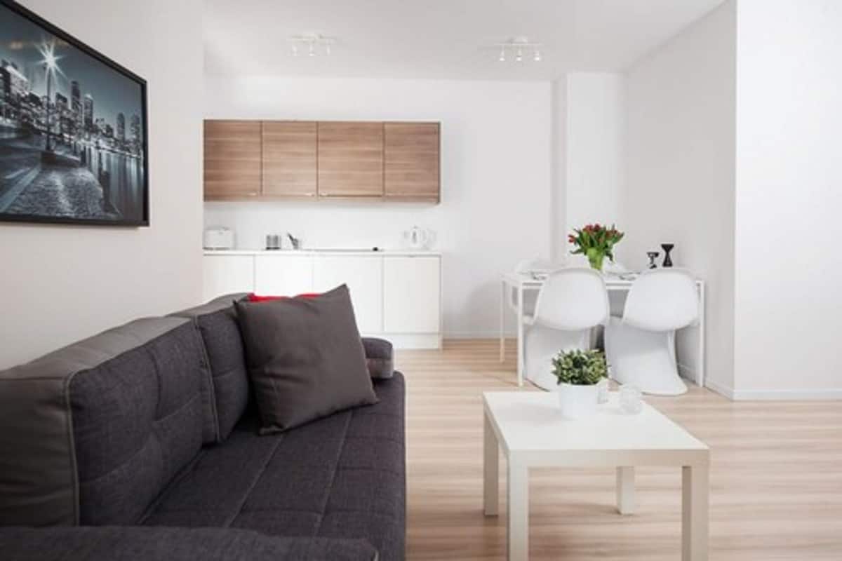 A modern living room with a grey sofa, a white coffee table, and a cityscape painting on the wall.