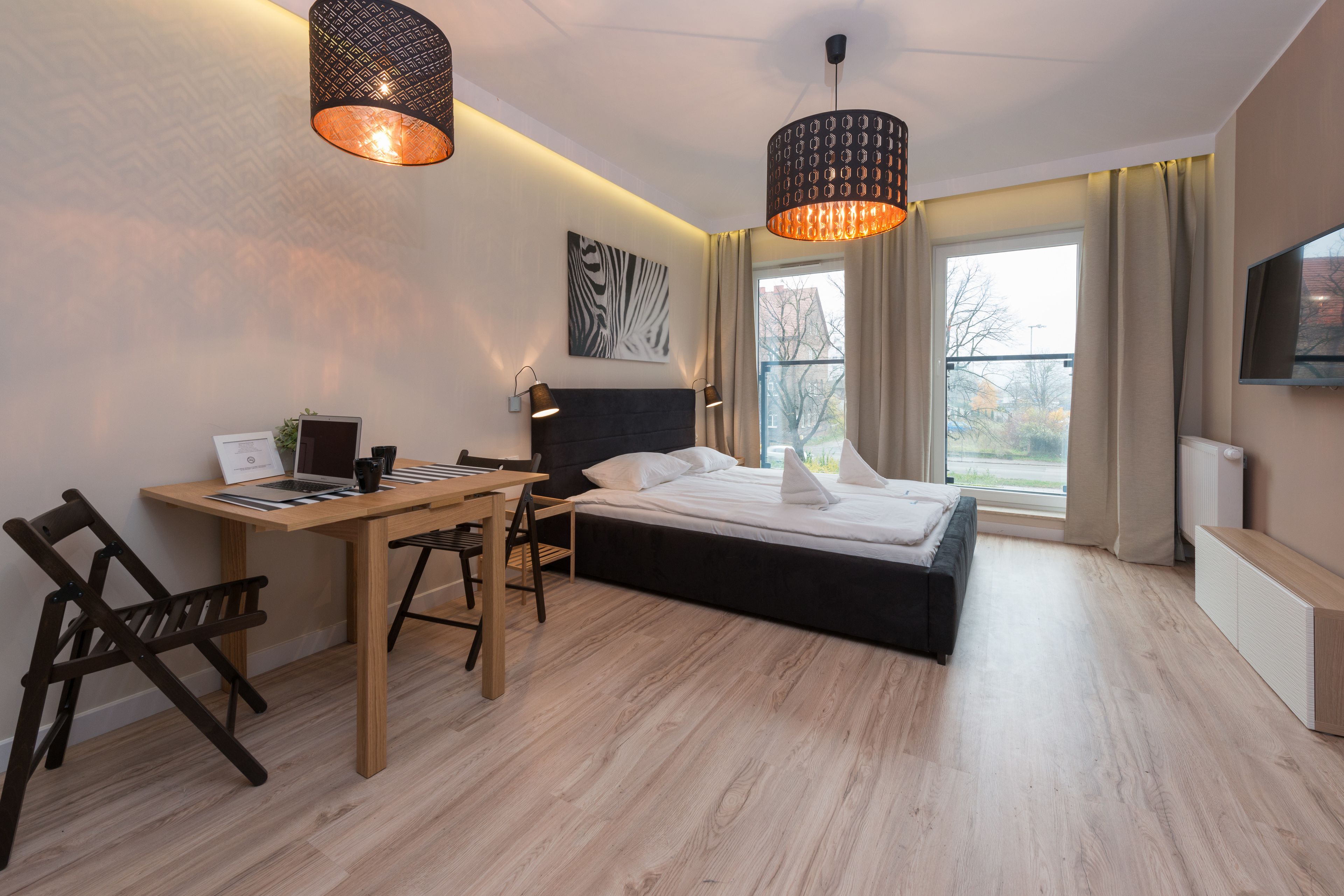 A modern bedroom with a bed, desk, and chairs.