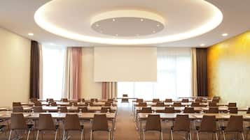 A conference room with a large screen, multiple tables, and chairs arranged for a meeting.