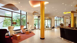 A spacious lobby with modern furniture, large windows, and a central column.