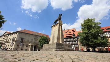 Una plaza adoquinada con una estatua de un oso sobre un pedestal, rodeada de edificios históricos con tejados de tejas rojas.