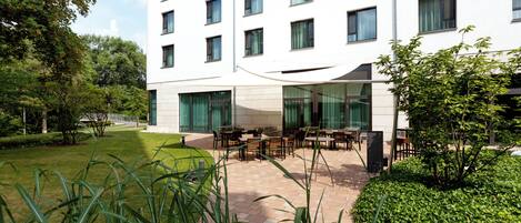 Un edificio moderno con patio interior que cuenta con mobiliario exterior y vegetación.