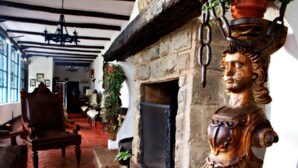 Una habitación tradicional con chimenea de piedra, muebles de madera y un candelabro.