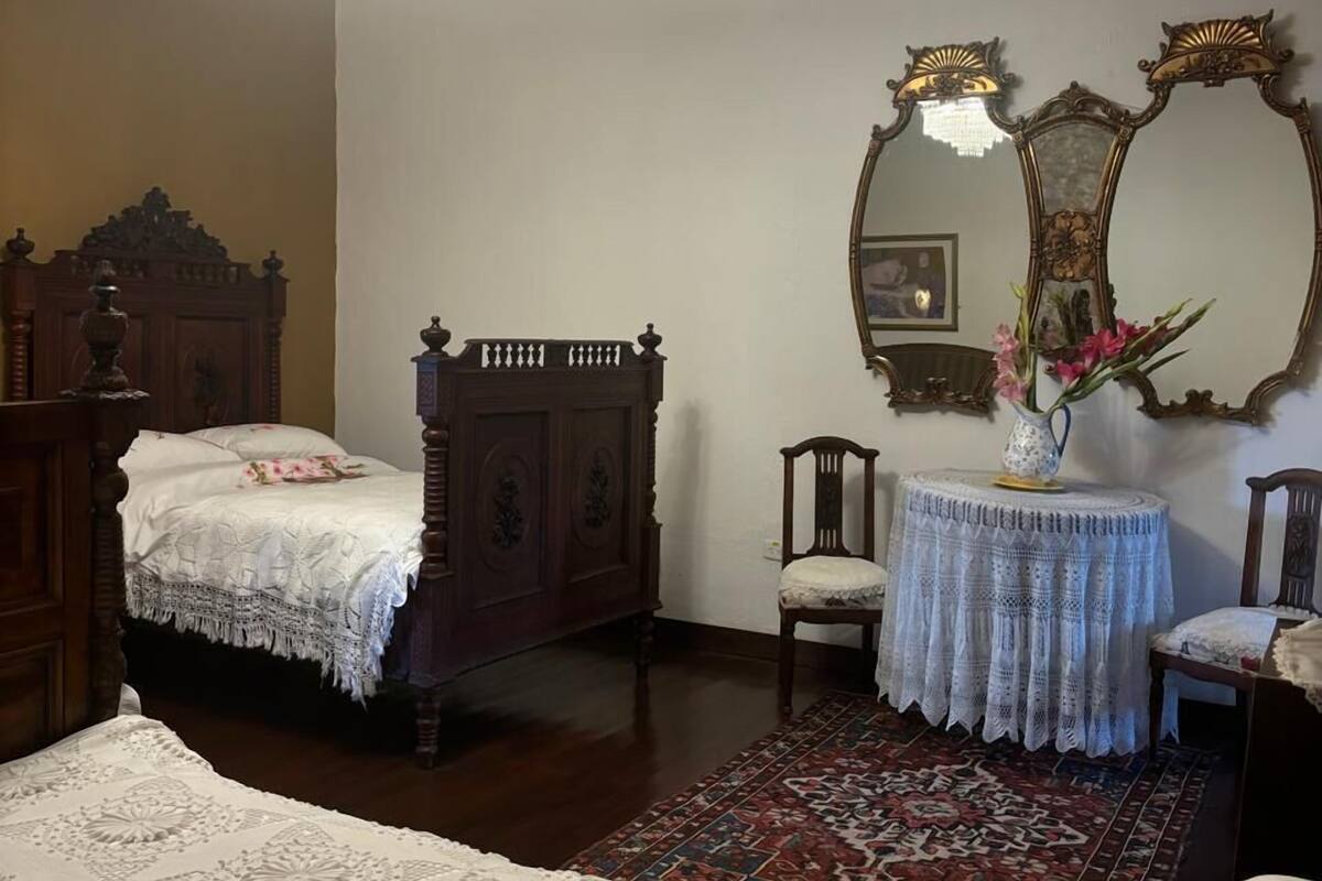 A traditional bedroom with a four-poster bed, a large ornate mirror, and a chandelier.