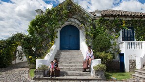 Un edificio con puerta azul, paredes blancas y una escalera de piedra que lleva a la entrada.