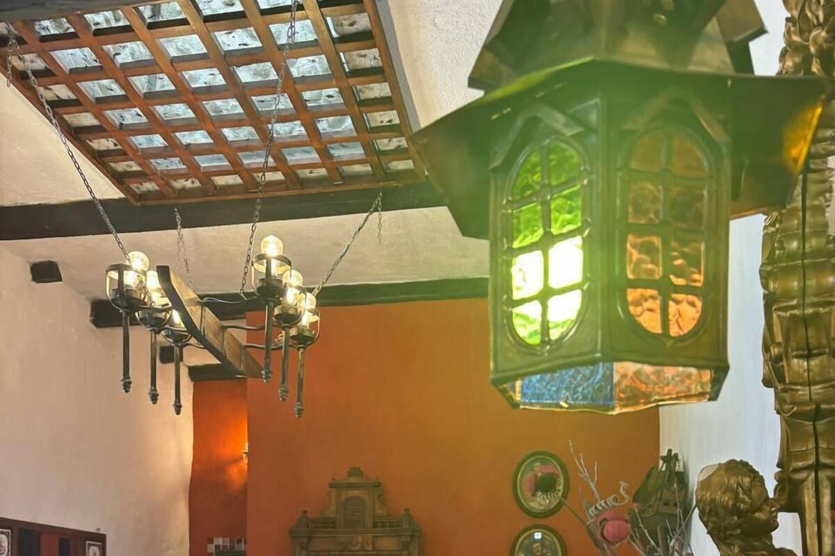 A traditional room with a wooden bed, a hanging light fixture, a green lantern, and a statue.