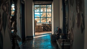 Un pasillo con un ventanal grande, una maleta y una silla.