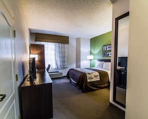 A hotel room with a bed, a desk, a television, a lamp, and a wall-mounted TV. - Sleep Inn Port St. Lucie at PGA Village (Port Saint Lucie)