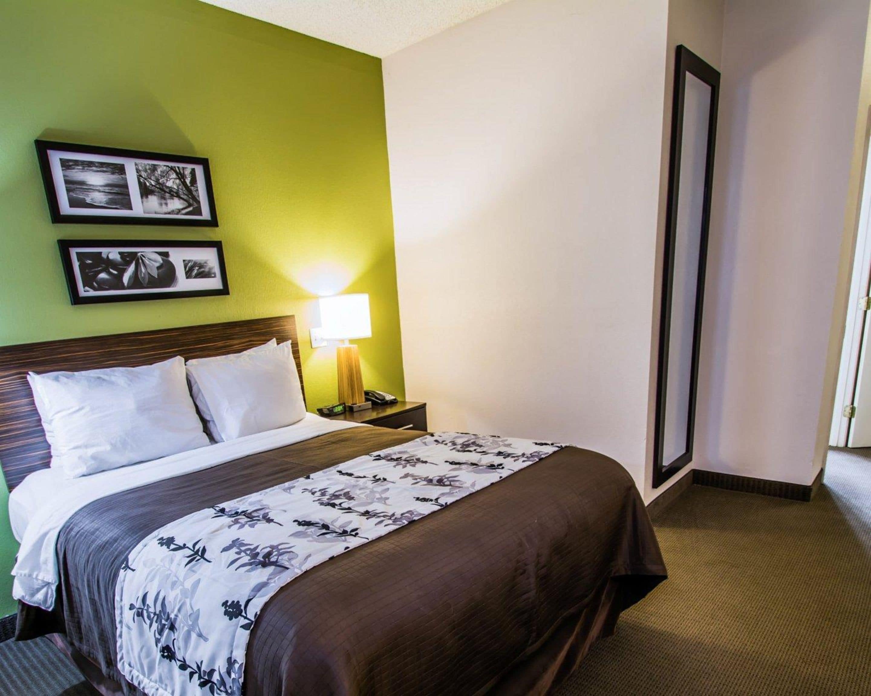 A hotel room with a large bed, a nightstand with a lamp, and two framed pictures on the wall.