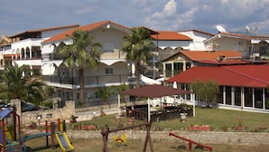 A residential building with multiple balconies, a playground, and a covered outdoor seating area. - Hanioti Grand Victoria (Kassandra)