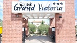 The entrance to Manjoti Grand Victoria with a brick facade and a sign above the entrance. - Hanioti Grand Victoria (Kassandra)