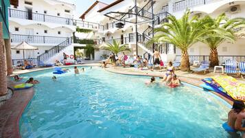 A swimming pool area with multiple levels of balconies, palm trees, and lounge chairs.