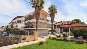 A multi-story building with balconies, palm trees, and a covered outdoor seating area. - Hanioti Grand Victoria (Kassandra)