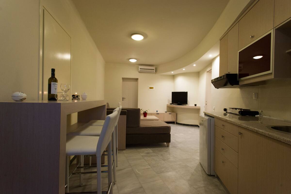 A compact kitchen with a dining area, a TV, and a refrigerator.
