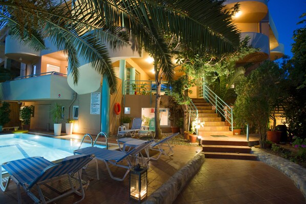 A pool area with lounge chairs and a staircase leading to an upper level. - Seafalios Apartments (Chania)