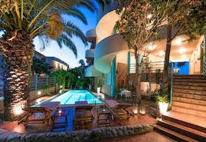 A poolside area with lounge chairs, a swimming pool, and a staircase leading to an upper level. - Seafalios Apartments (Chania)