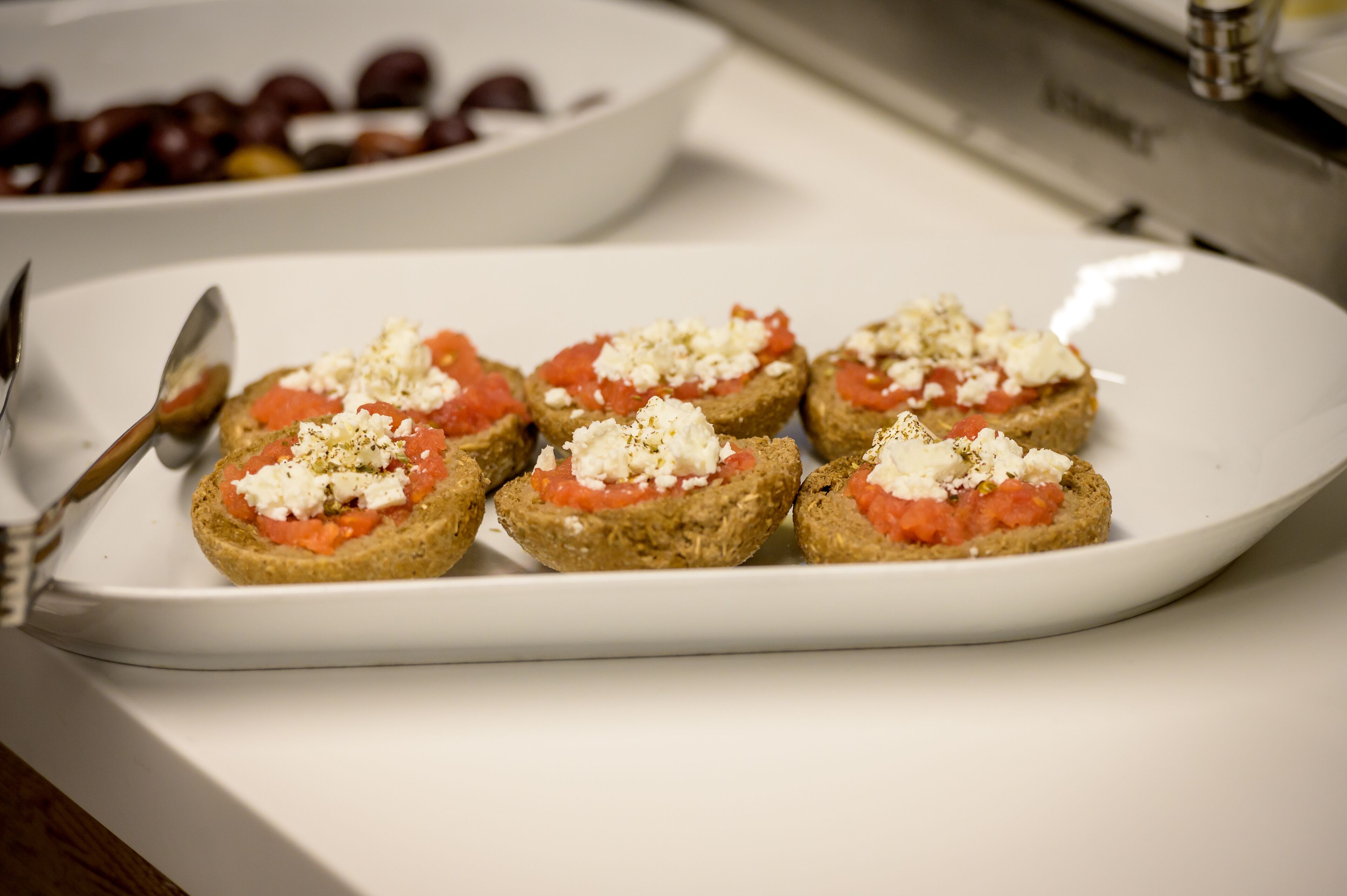 A plate with five open-faced sandwiches topped with tomato and cheese.