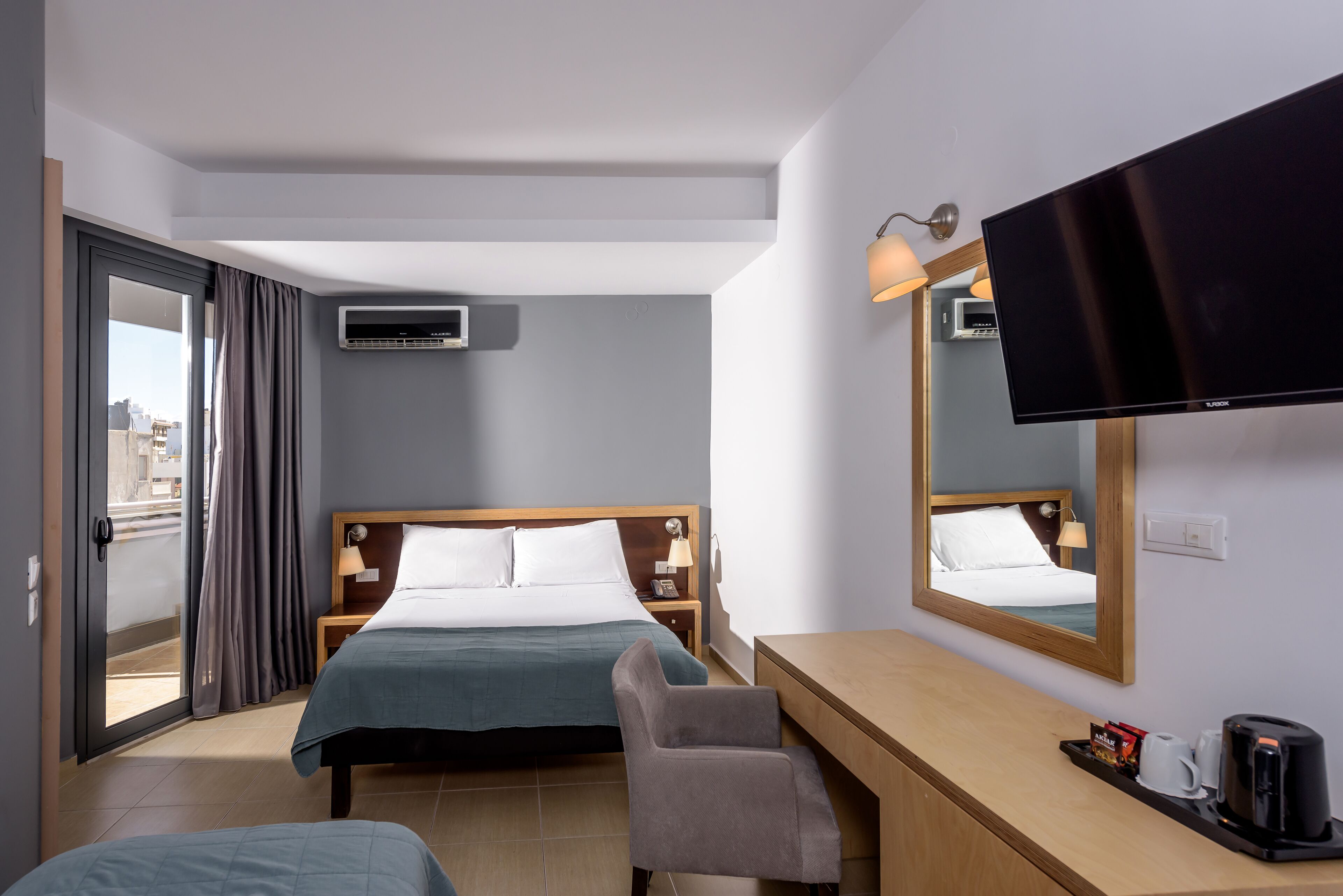 A hotel room with a bed, a desk, a chair, a television, and a window with curtains.
