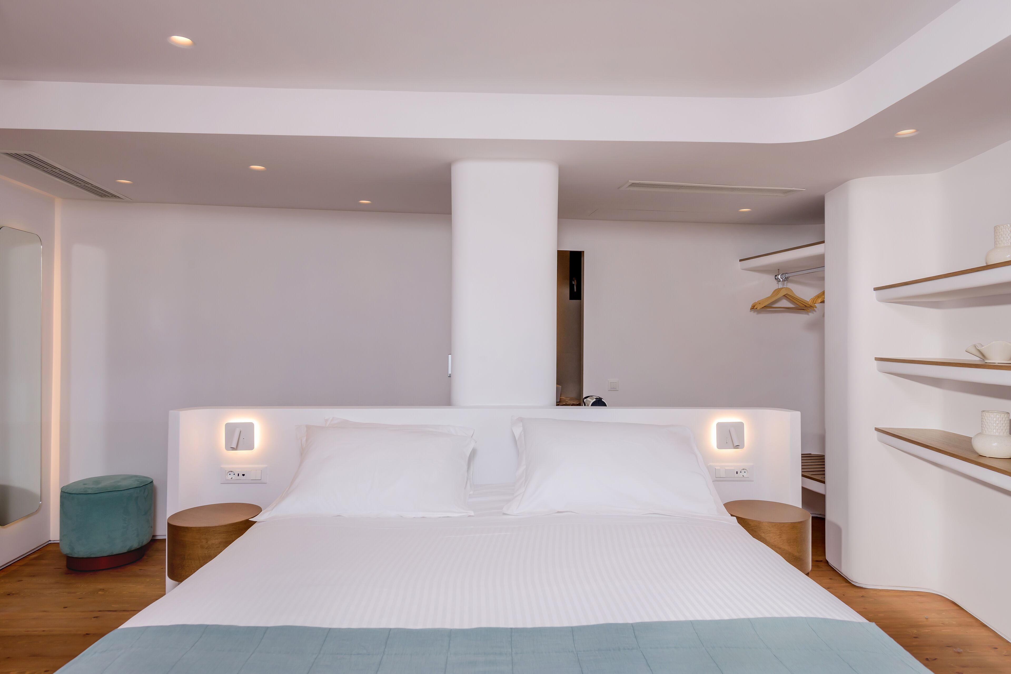 Una camera da letto moderna con un letto grande, comodini, uno specchio e un armadio con ripiani.
