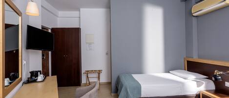 A hotel room with a bed, a desk with a chair, a television, and a mirror.