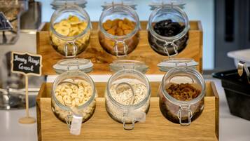 Una barra de desayuno con diversos alimentos en frascos de vidrio, como cereales y frutos secos.
