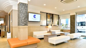 A modern hotel lobby with a reception desk, seating area, and a large screen displaying the hotel name. - New Commander Hotel Osaka Neyagawa (Neyagawa)
