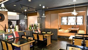A restaurant interior with tables and chairs, a counter with bottles, and a window with a view. - New Commander Hotel Osaka Neyagawa (Neyagawa)
