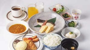 Une table où l’on trouve divers plats, notamment de la soupe, du riz, des légumes et un croissant.