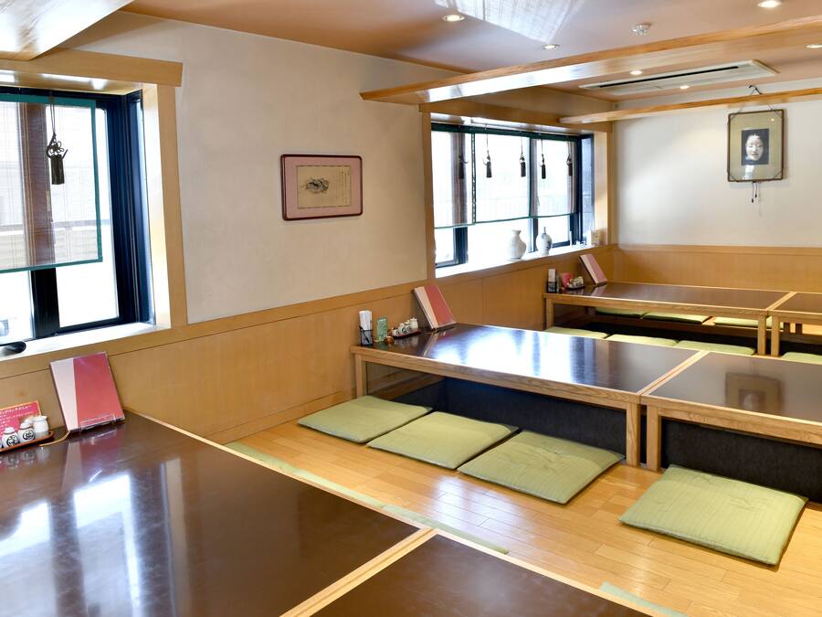 Une pièce traditionnelle japonaise avec des tatamis, de petites tables basses et des coussins.