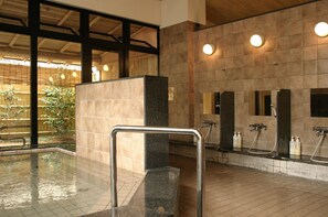 Un espace de bains public comprenant une piscine, des murs carrelés et des barres d’appui.