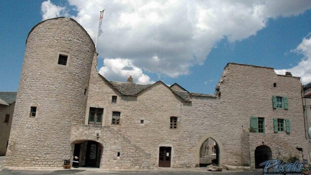 A stone building with a round tower, multiple windows, and an archway entrance.