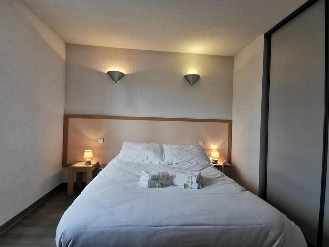 Una habitación de hotel con una cama, dos lámparas de noche y un cabecero.