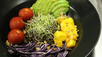 A black plate with a variety of food items including avocado, mango, red cabbage, and sprouts.