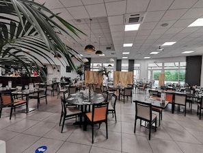 A spacious dining area with multiple tables and chairs, large windows, and a ceiling with recessed lighting. - Hotel de la Poste (La Cavalerie)