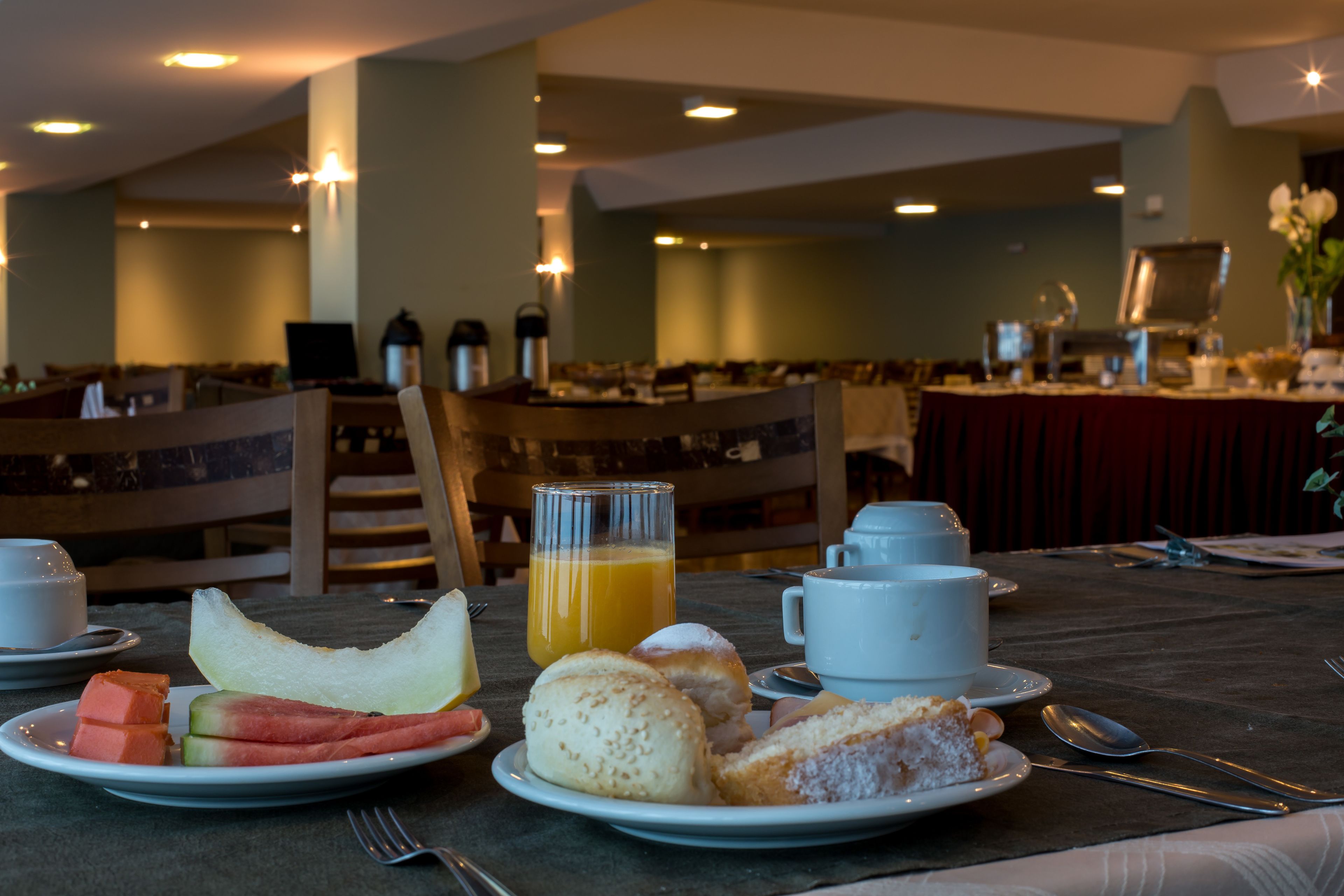 A breakfast setting with plates of food, a glass of orange juice, and a cup of coffee on a wooden table.